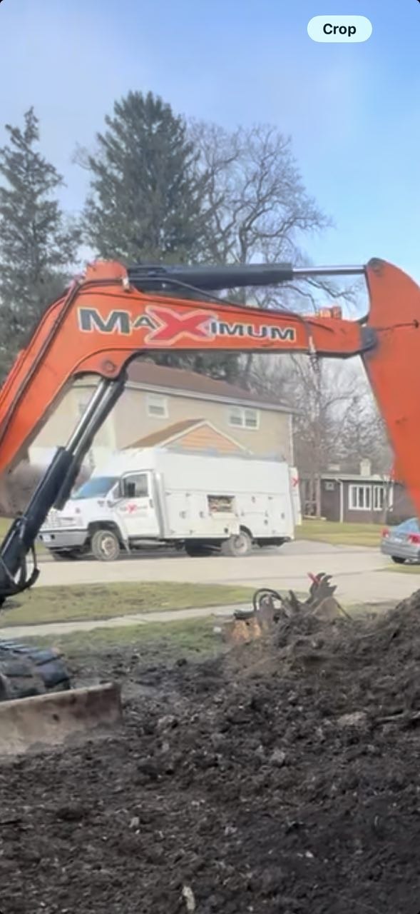Orange Hitachi excavator with MAXIMUM branding performing residential trench dig